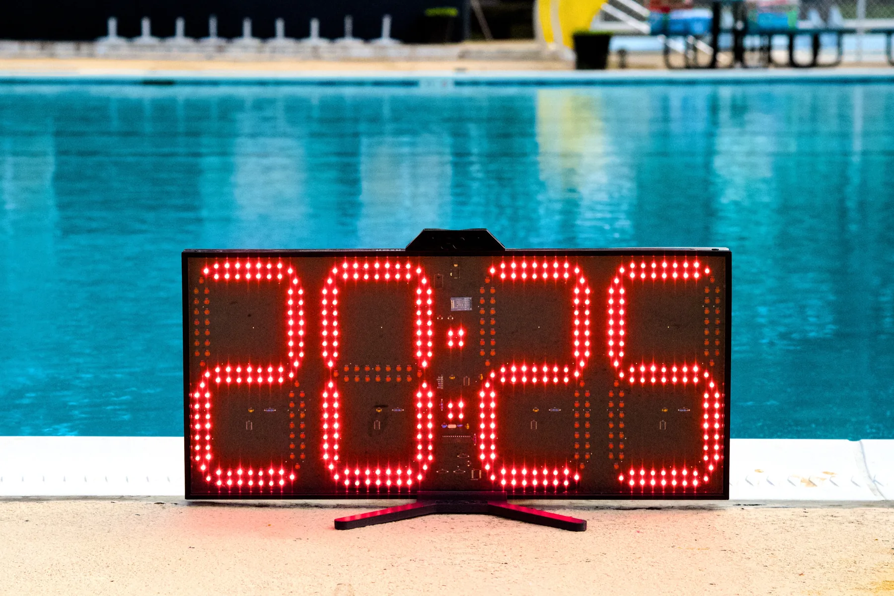 A Neon pace clock on the deck of an outdoor pool