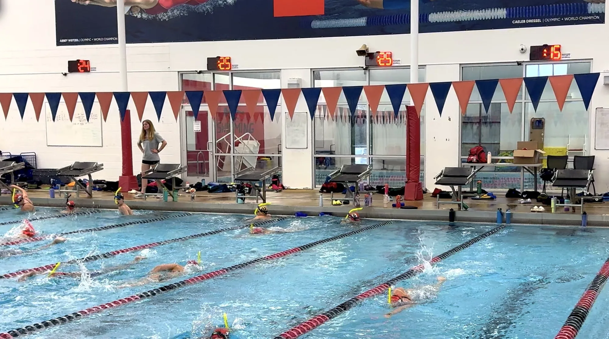 A coach at practice with four Neon pace clocks on the wall